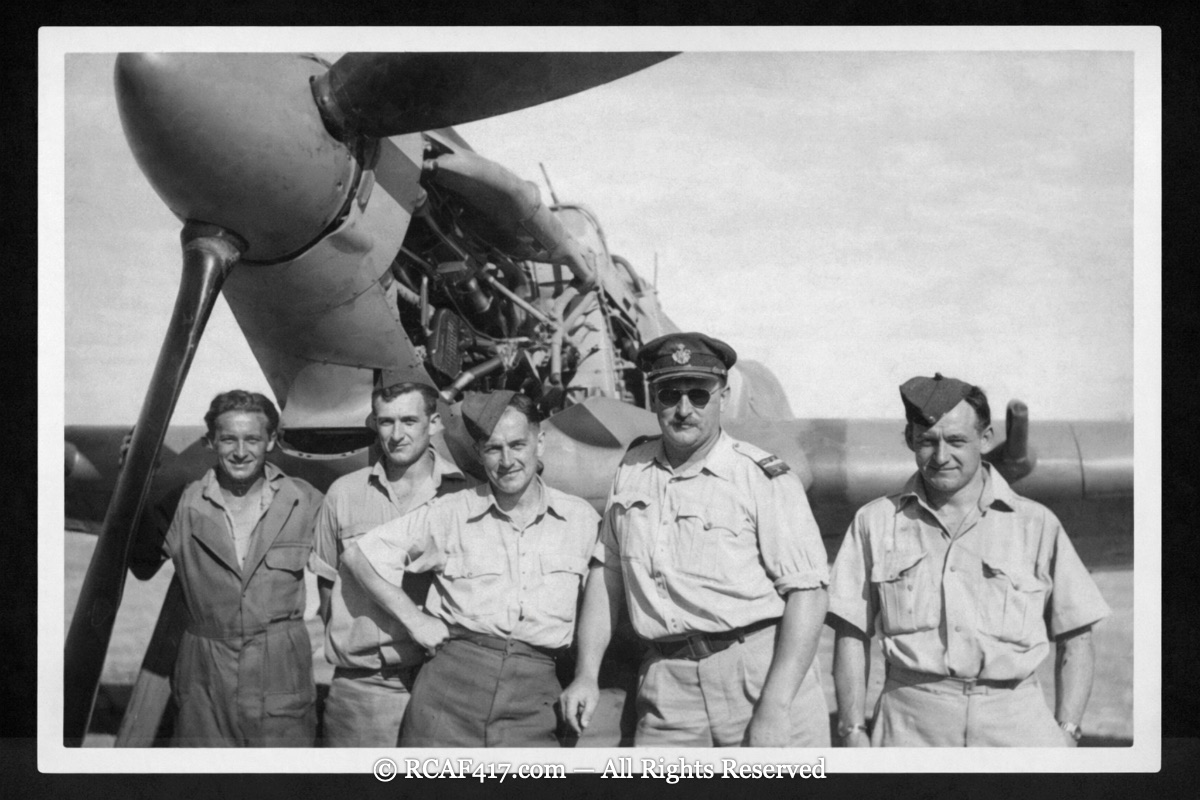 Five 417 Squadron airmen posed beside a Spitfire's engine and propeller in the desert