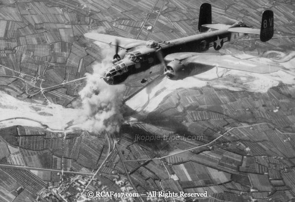 A B-25 Mitchell coded 8V banking over a target with smoke visible below