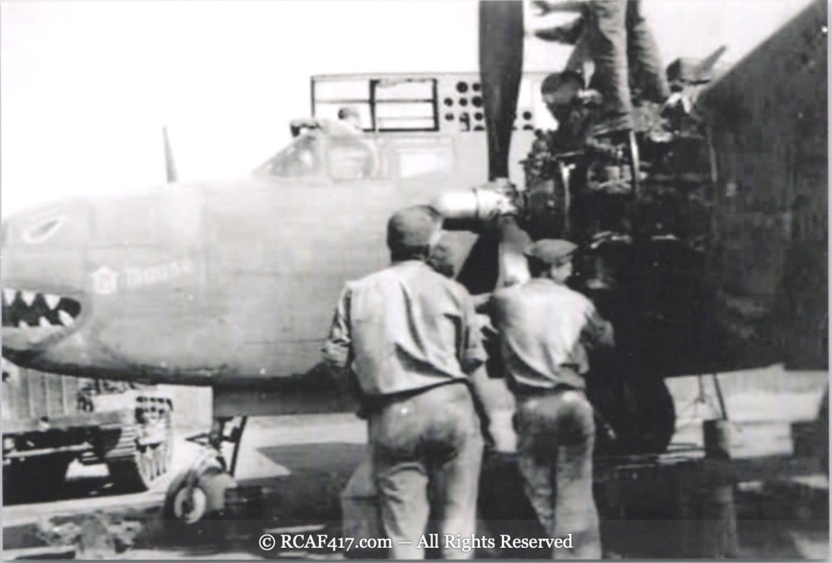 Ground crew servicing a B-25 with a shark-mouth nose, name partly reading Bouise