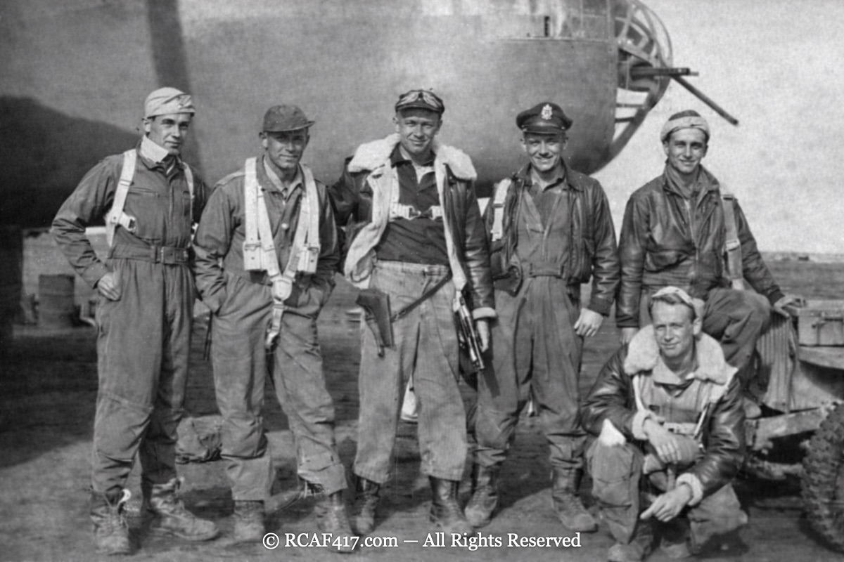 Six airmen posed in front of a B-25's nose turret