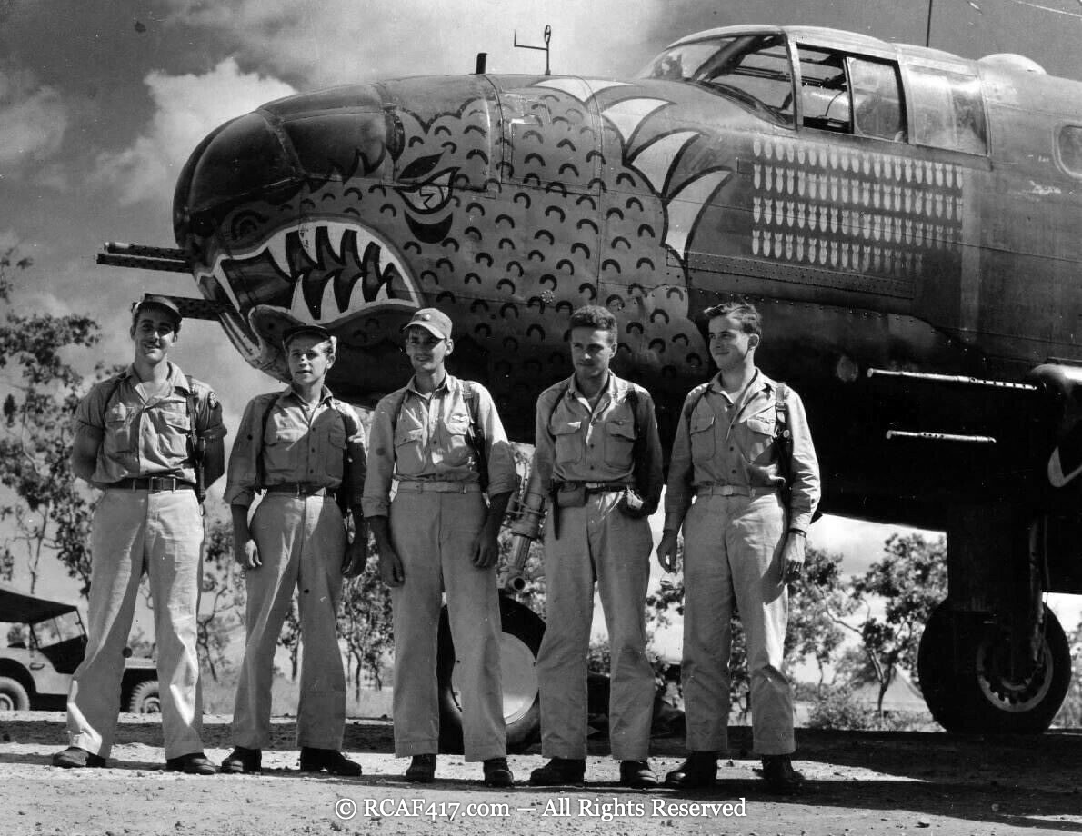 Five-man crew posed in front of a B-25 with a large shark-mouth nose and mission tally marks