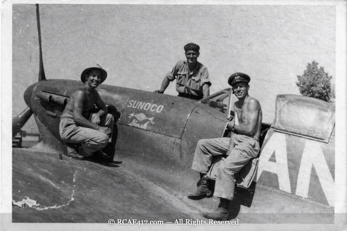 Ground crew and a pilot relaxing on a Spitfire marked with Sunoco nose art, Egypt